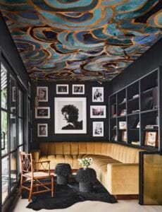 "Interior with fabulous ceiling art, black walls adorned with framed artwork, and a yellow sofa."